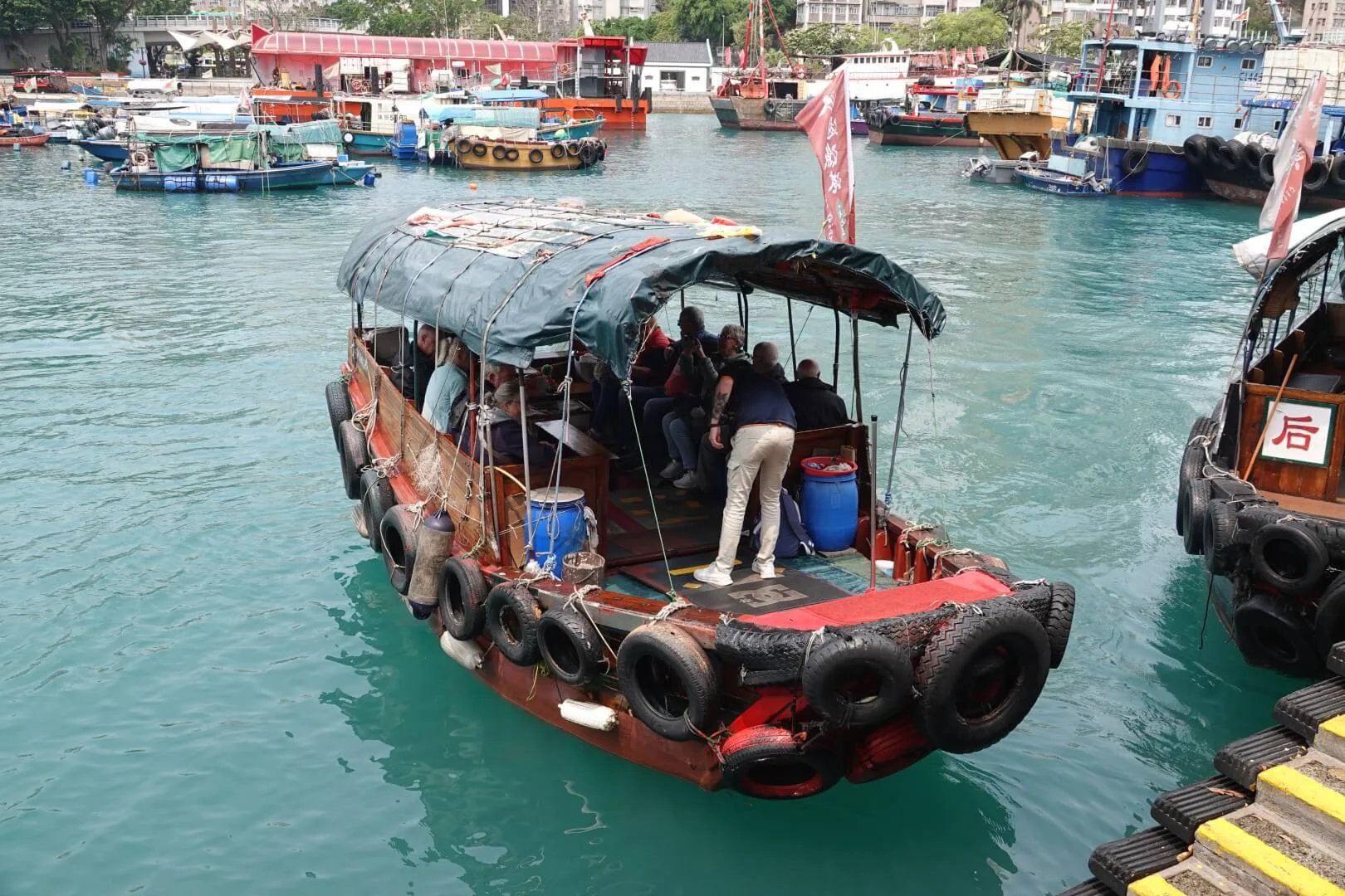 A traditional sampan boat departs from the harbor.