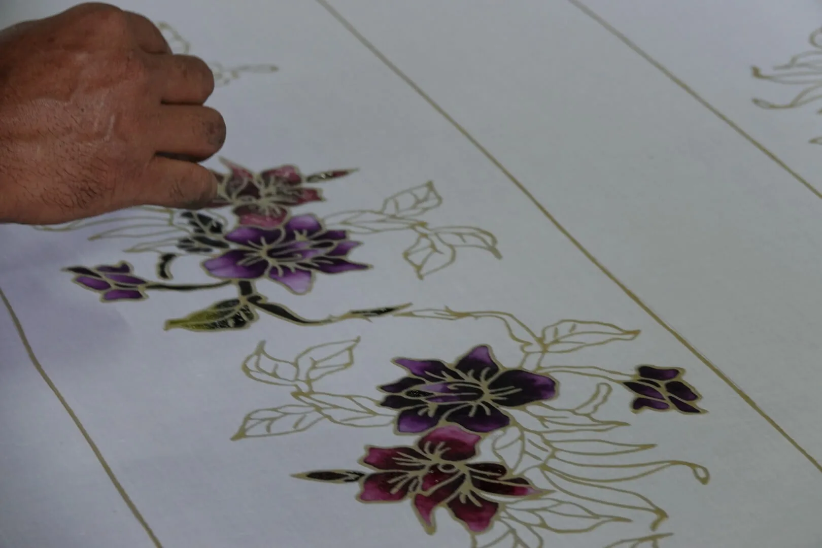 An artisan carefully paints the floral patterns by hand.
